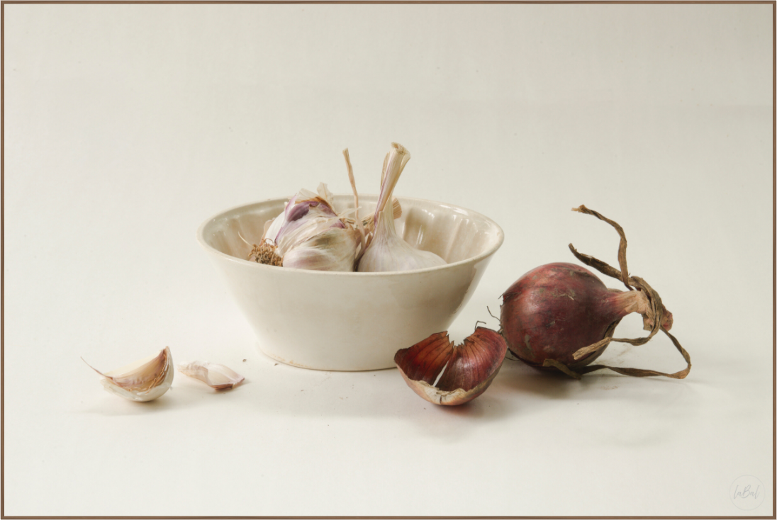 Realistisch stilleven met knoflookbollen in een crèmekleurige puddingvorm en een roodbruine ui op een lichte achtergrond.