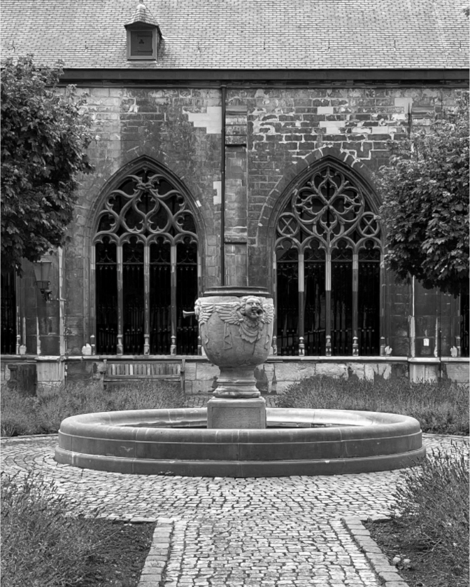 Zwart-witfoto van fontein in Sint Servaastuin Maastricht met gotische ramen op achtergrond – fine art print van Dirk Bal.