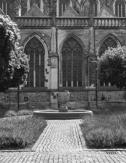 Zwart-witfoto van fontein in Sint Servaastuin Maastricht met gotische ramen op achtergrond – fine art print van Dirk Bal.