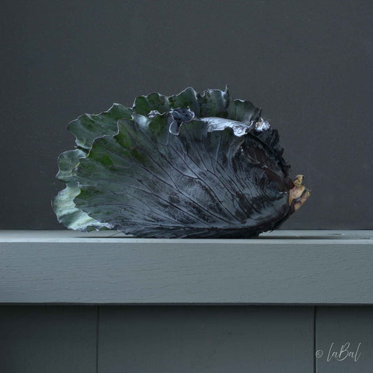Realistisch stilleven van een rode kool op een lichtgroen oppervlak, met gedetailleerde, glanzende bladeren en een rustige, neutrale achtergrond. Kunstwerk van Dirk Bal.