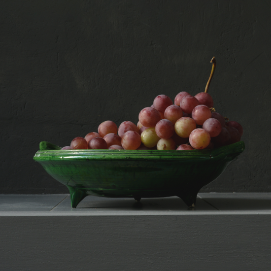 Realistisch stilleven van rode druiven in groene schaal – fine art print van Dirk Bal.